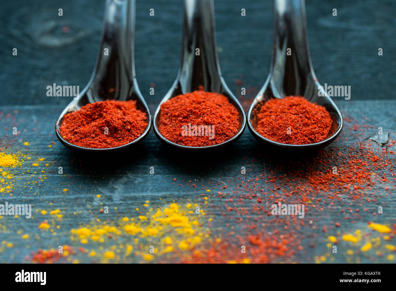 Vue de dessus de cuillères remplies d'épices paprika rouge foncé sur fond de bois recouverts de paprika et de curry en poudre Banque D'Images Vue de dessus de cuillères remplies d'épices paprika rouge foncé sur fond de bois recouverts de paprika et de curry en poudre Banque D'Images