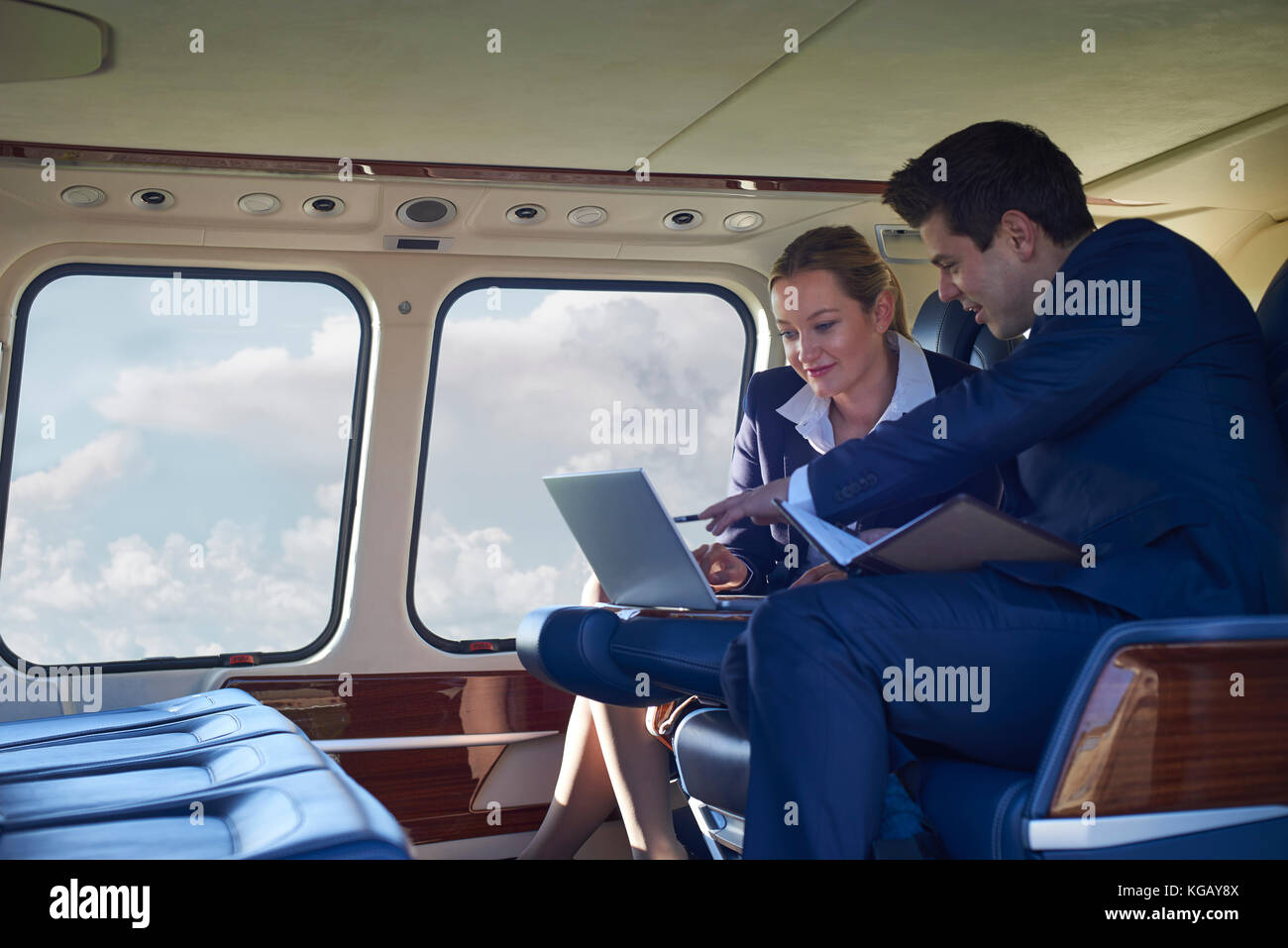 Businessman and businesswoman working on laptop in cabine de l'hélicoptère Banque D'Images