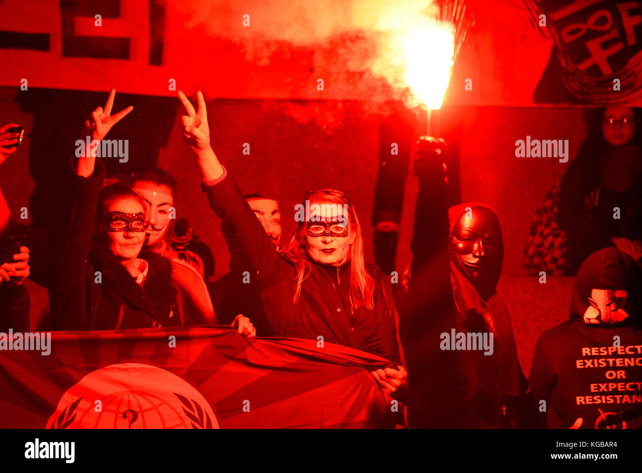 Flare enflammé à Millions Mars masque pour les sans-voix anonyme manifestation de protestation à travers Londres sur la nuit de Guy Fawkes, le 5 novembre. Lueur rouge Banque D'Images