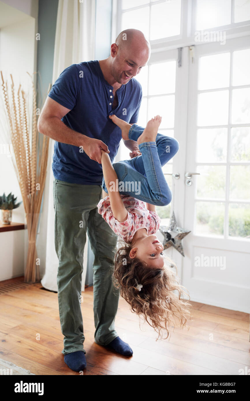Girl holding her dad's mains et faire un saut périlleux à la maison Banque D'Images