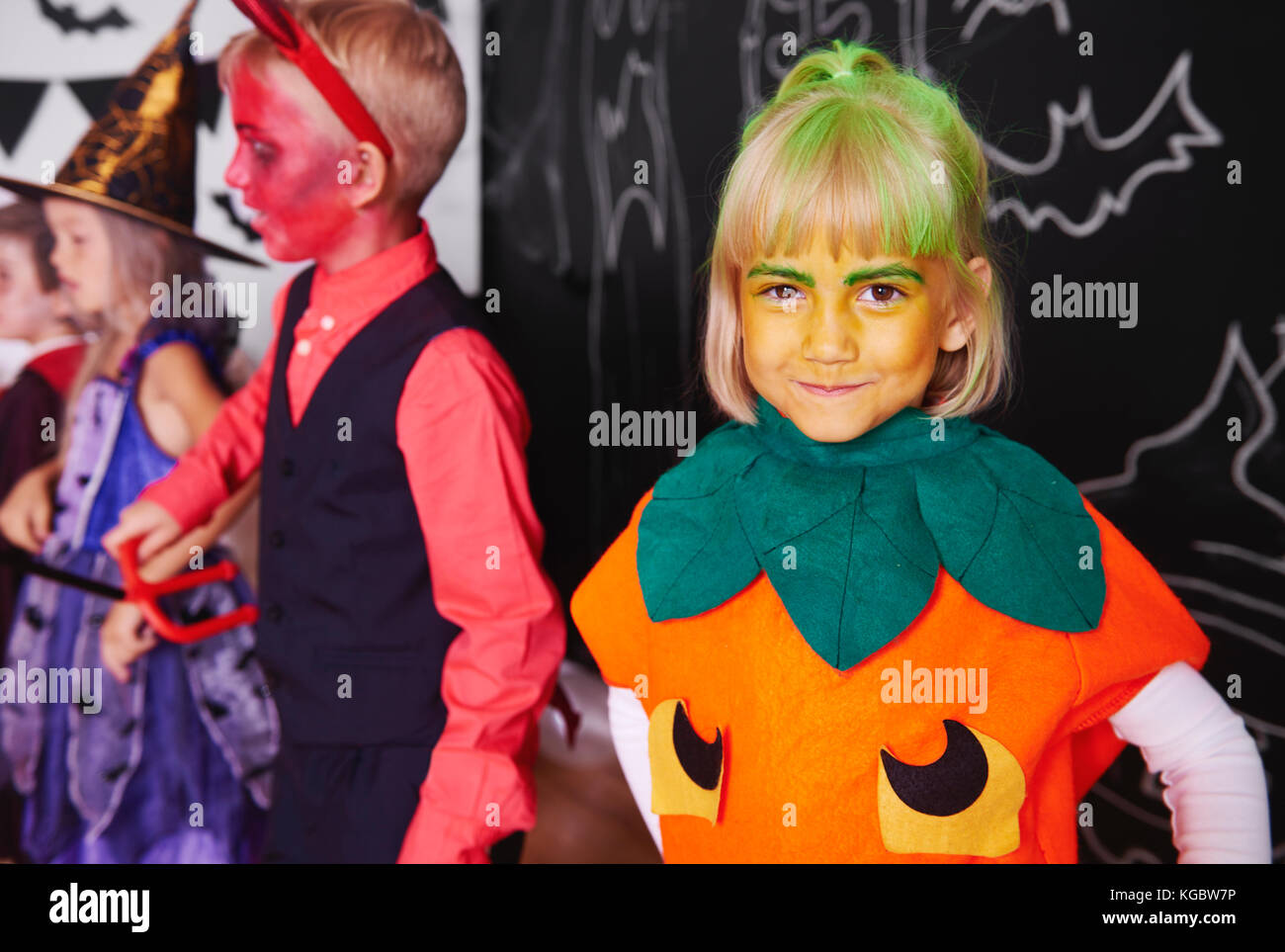 Jolie fille en costume de citrouille célébrer Halloween avec des amis Banque D'Images