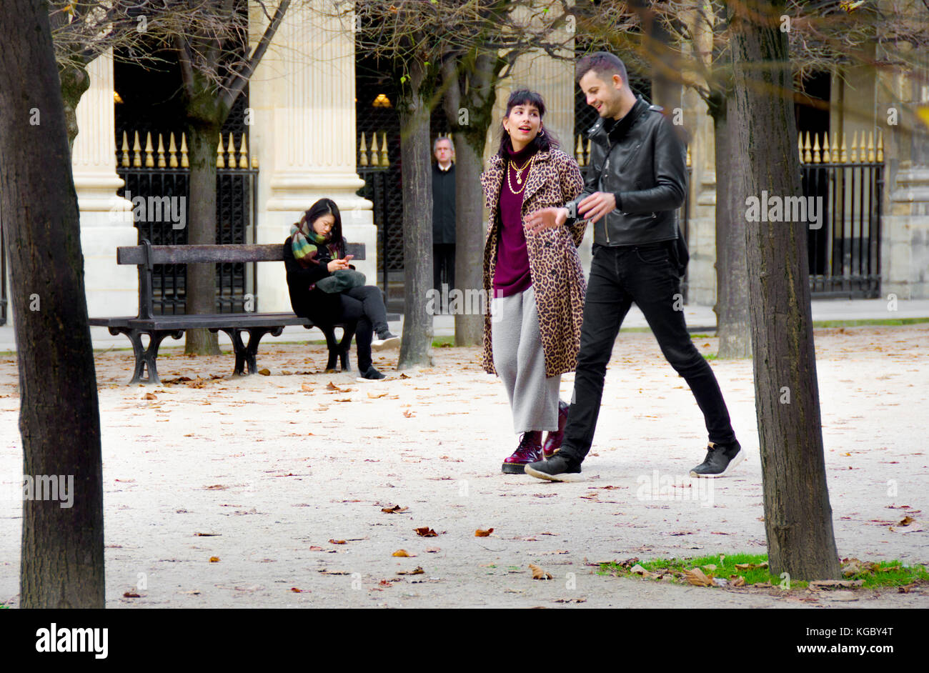 Paris, France. Palais Royal. L'automne, woman sur un banc, young couple walking passé (et un homme effrayant entre les arbres) Banque D'Images