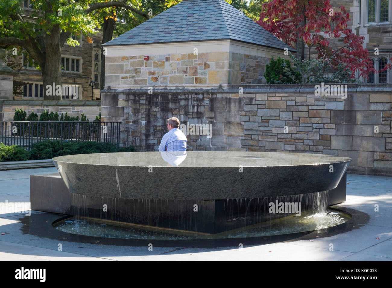 Homme assis à côté de la fontaine Banque D'Images