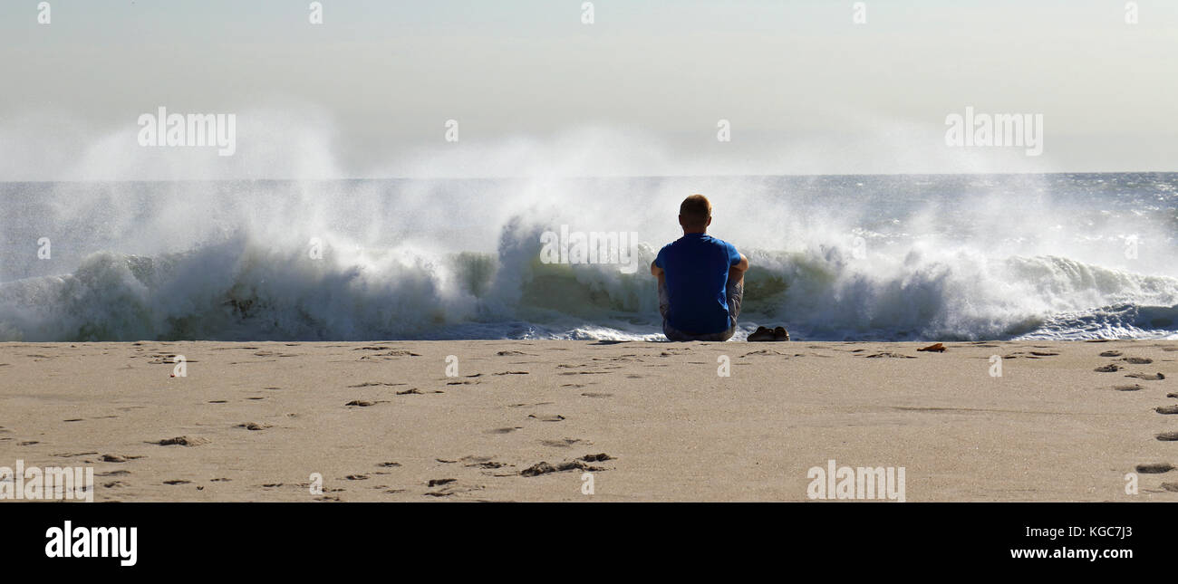 Une plage goer prend le temps de regarder les forces de la nature au travail comme ces grosses vagues crach le long du littoral Banque D'Images