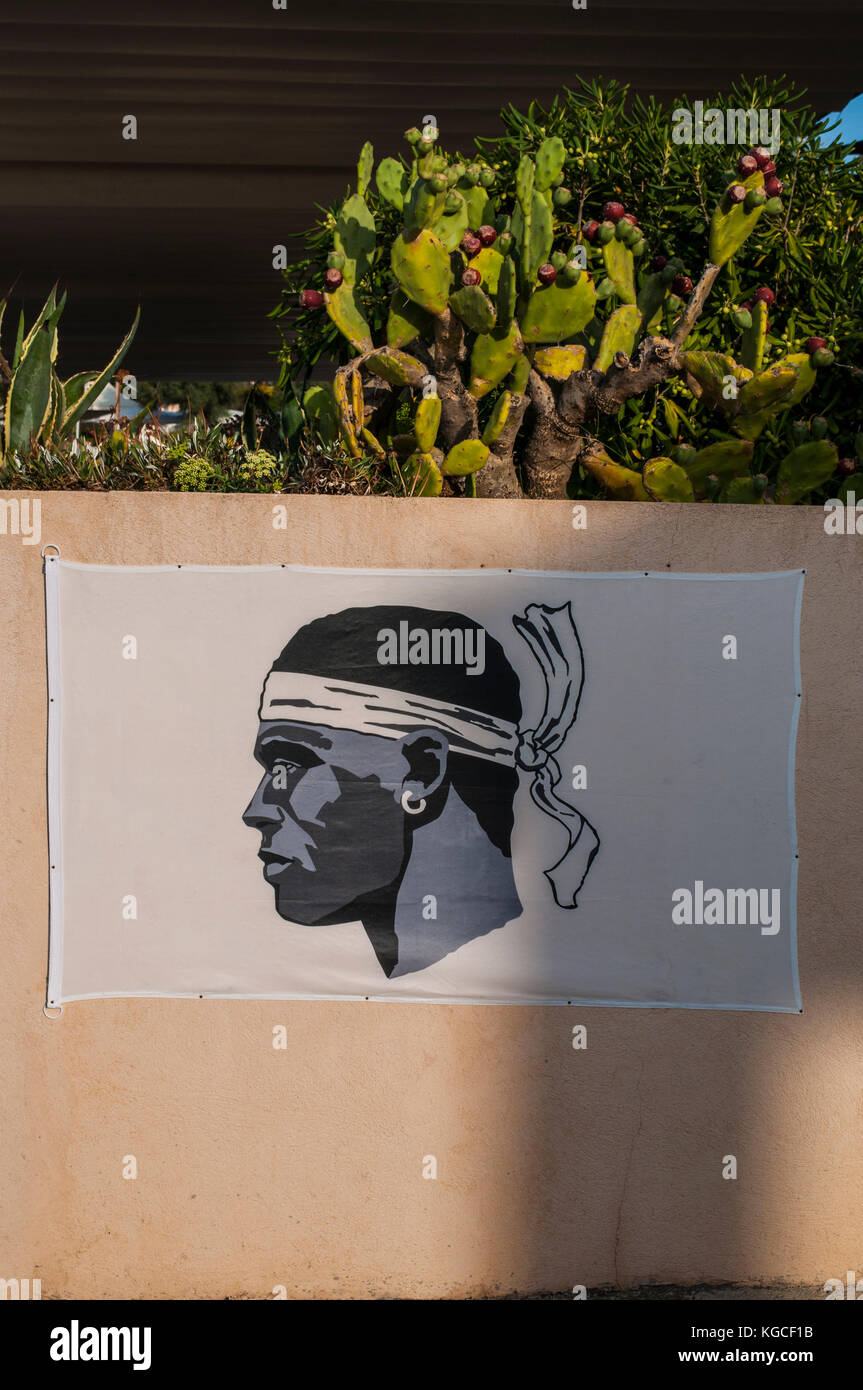 Corse : le drapeau de la Corse, une tête de maure en noir portant un foulard blanc au-dessus de ses yeux et noués sur le cou, accrochée à un mur rose à centuri Banque D'Images