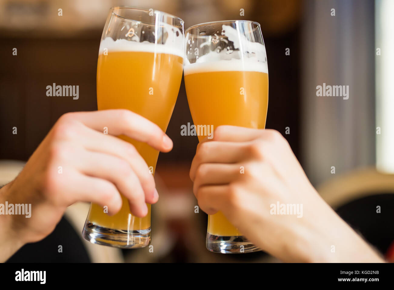 Les hommes avec de la bière cheers dans les verres dans un pub. Banque D'Images