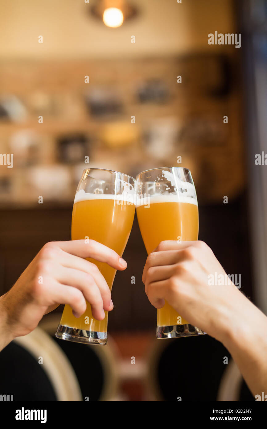 Les hommes avec de la bière cheers dans les verres dans un pub. Banque D'Images