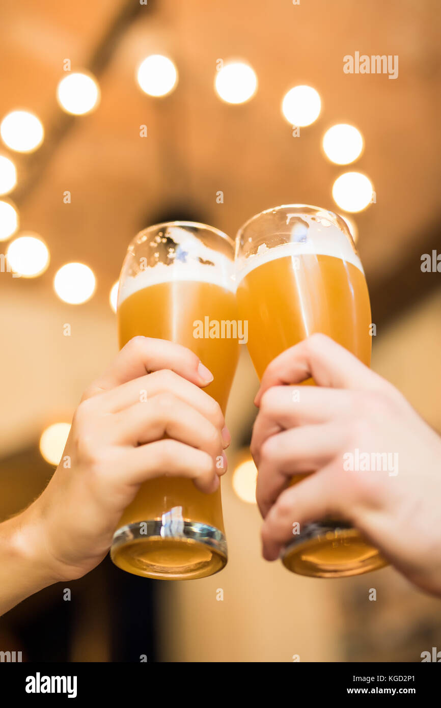 Les hommes avec de la bière cheers dans les verres dans un pub. Banque D'Images