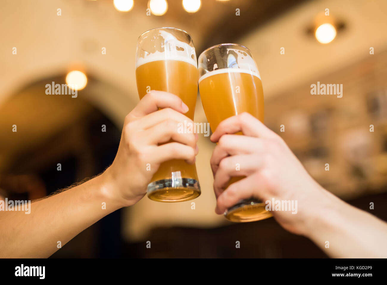 Les hommes avec de la bière cheers dans les verres dans un pub. Banque D'Images