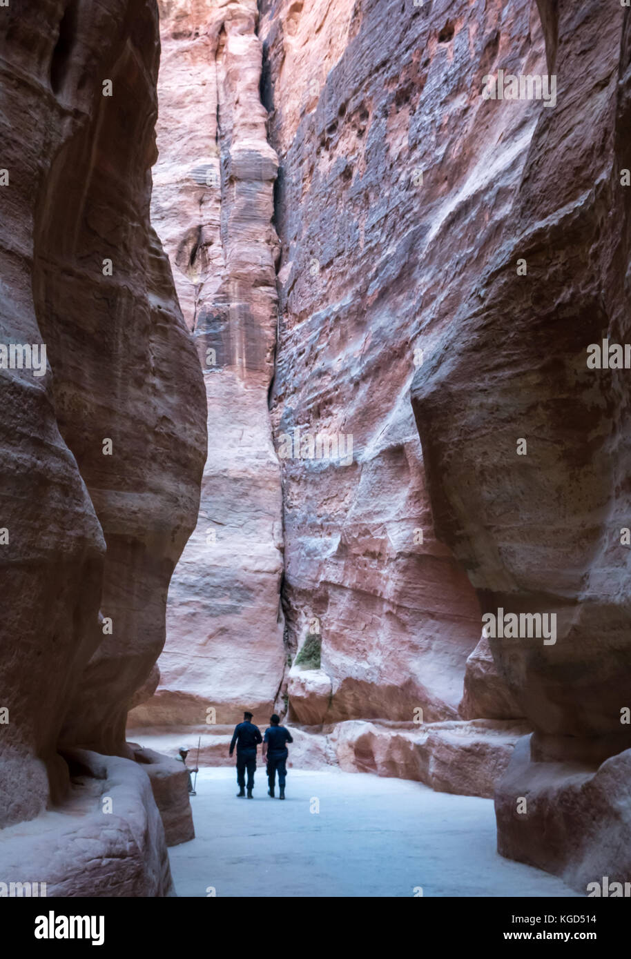 Deux policiers marchant à travers haute falaise murs de la Siq en gorge tôt le matin, Petra, Jordanie, Moyen-Orient Banque D'Images