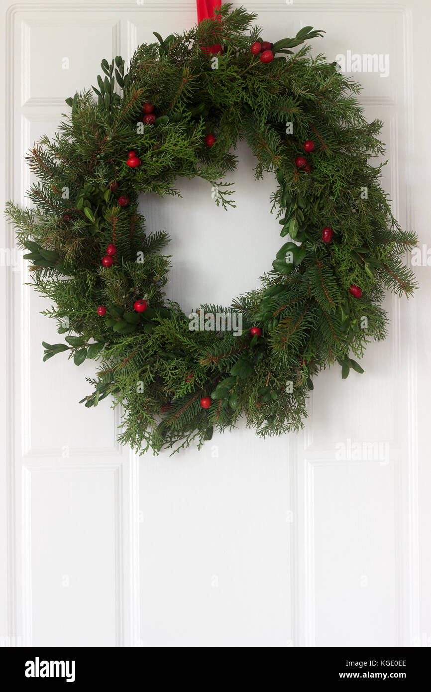 Handmade est une couronne de Noël en épinette, thuya, genévrier, buis et Wild Rose fruits rouges ornant la porte d'entrée. focus sélectif. Banque D'Images