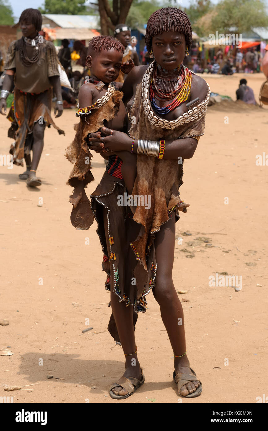 Turmi, vallée de l'Omo, Ethiopie - Juillet 29 : portrait de la jeune fille avec de l'enfant sur les mains de hamer personnes reposant sous l'arbre en transit Banque D'Images