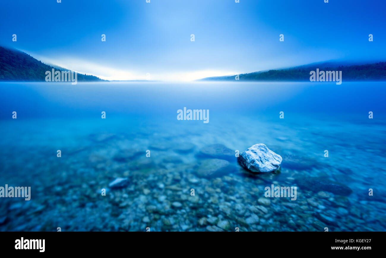 Une longue exposition rock dans le lac, à Pebble Beach en bleu lumière du matin. Banque D'Images