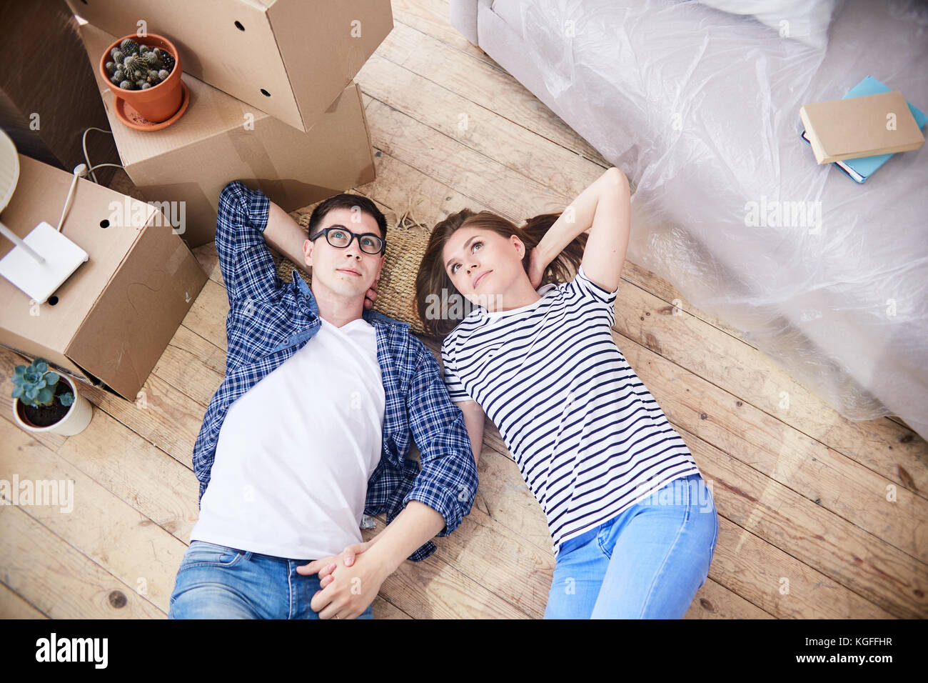 High angle view of loving young couple lying on floor de salon et à rêver de leur cohabitation dans de nouvelles vacances, pile de cartons de déménagement stan Banque D'Images