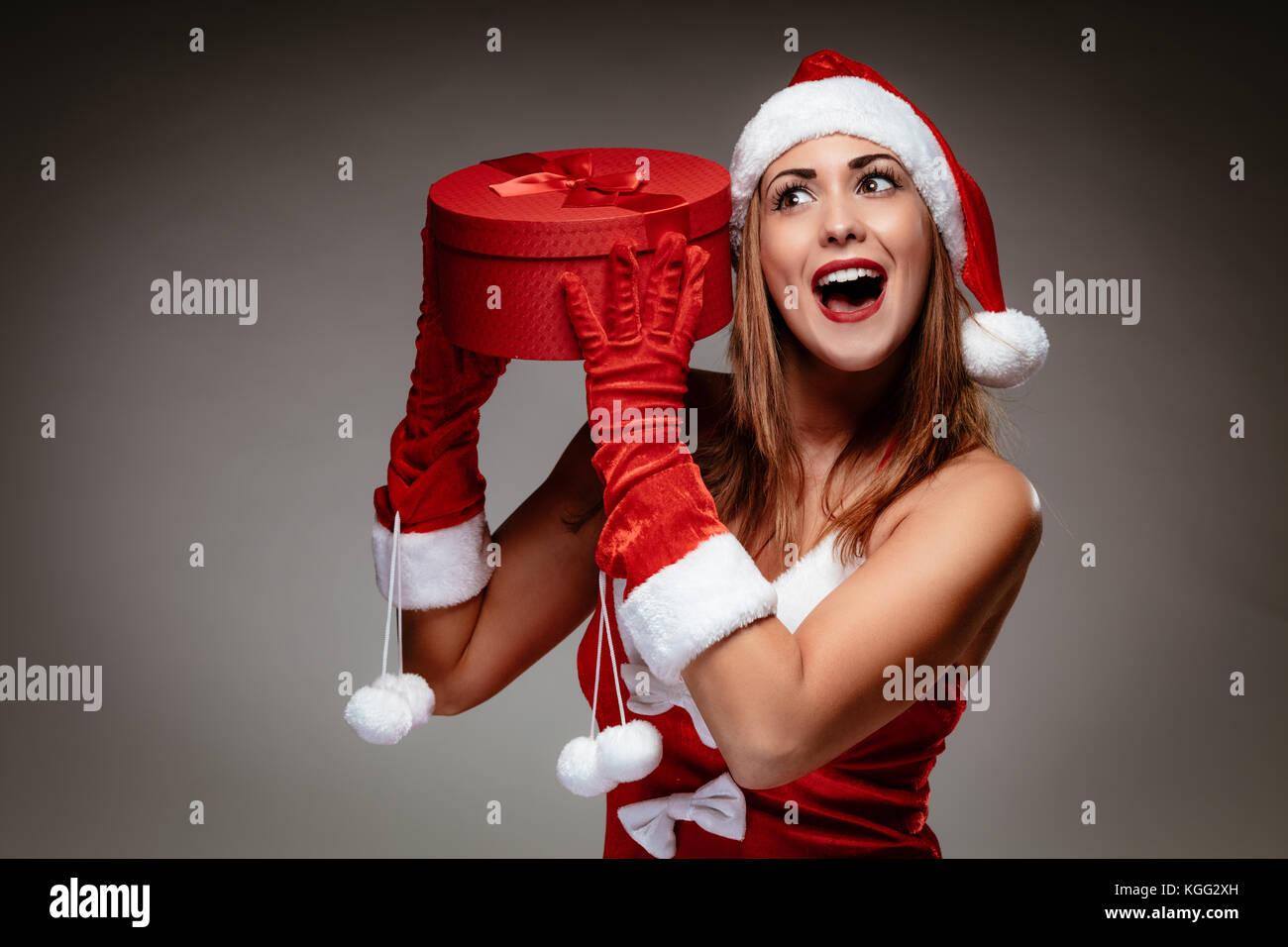 Belle jeune femme en costume père noël holding red présents et d'avoir du plaisir. Banque D'Images