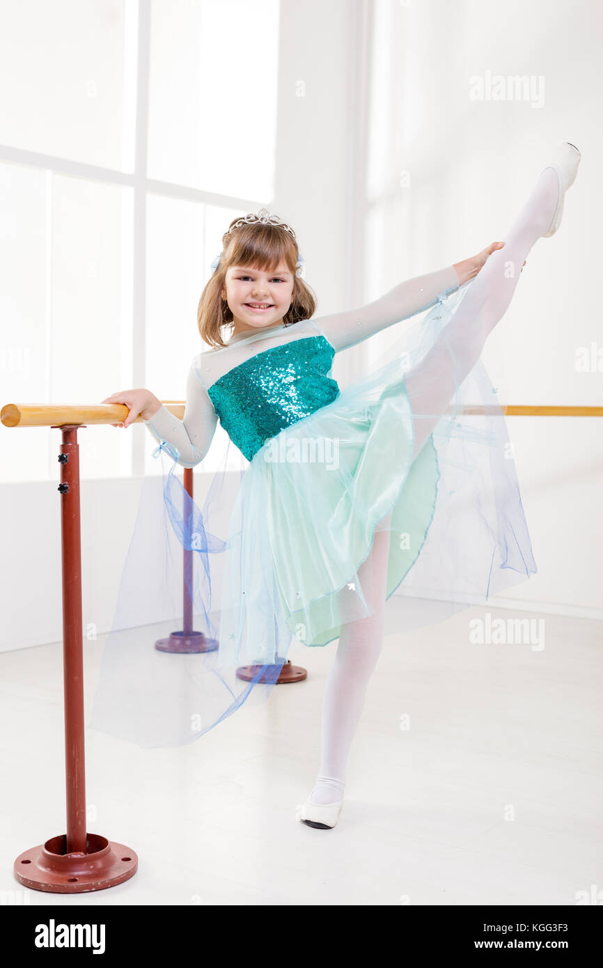 Cute smiling little girl en utilisant barre tout en pratiquant dans un studio de danse. Banque D'Images