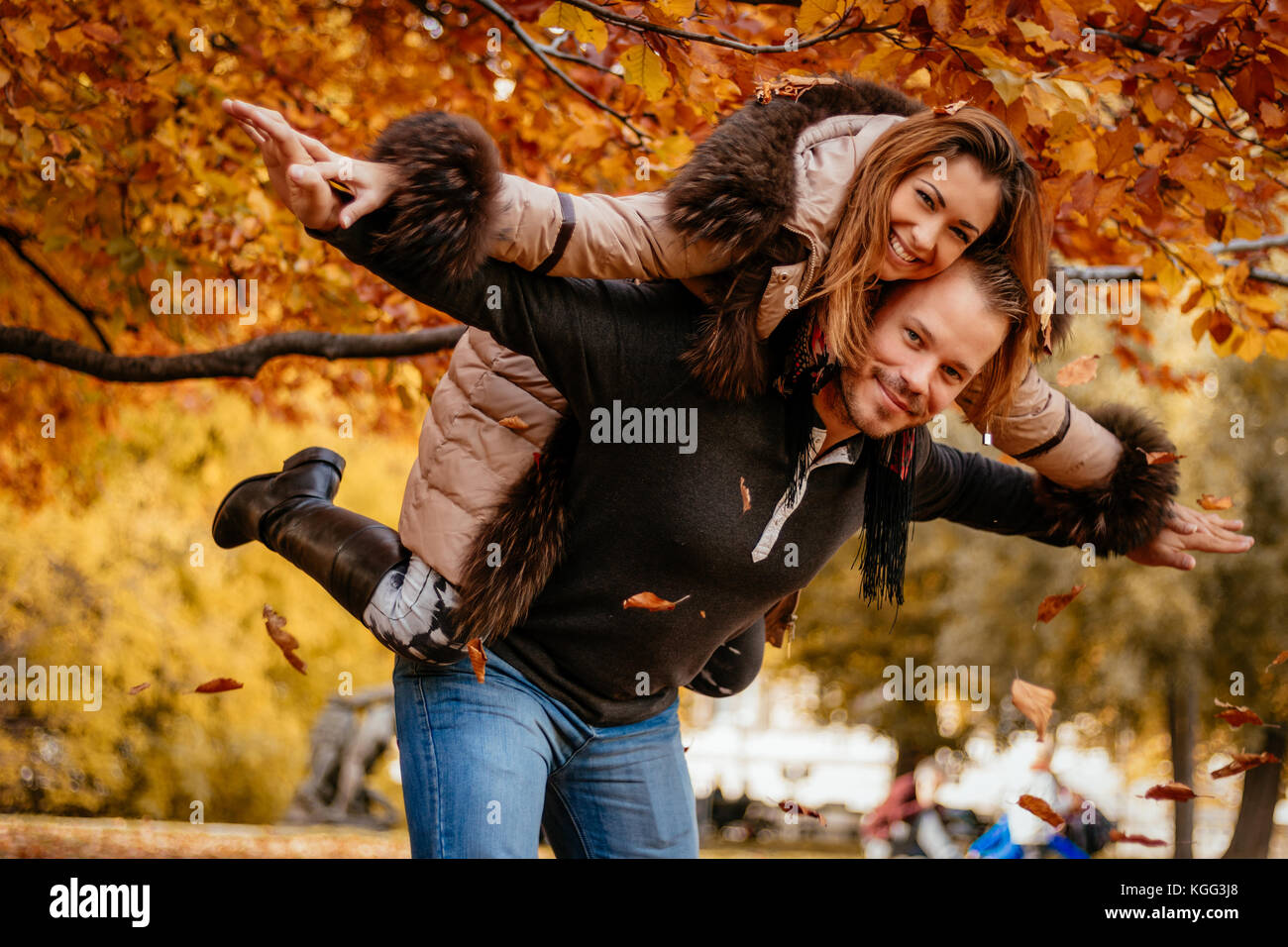 Beau jeune couple bénéficiant d'un parc ensoleillé de ferroutage dans couleurs d'automne. looking at camera. Banque D'Images