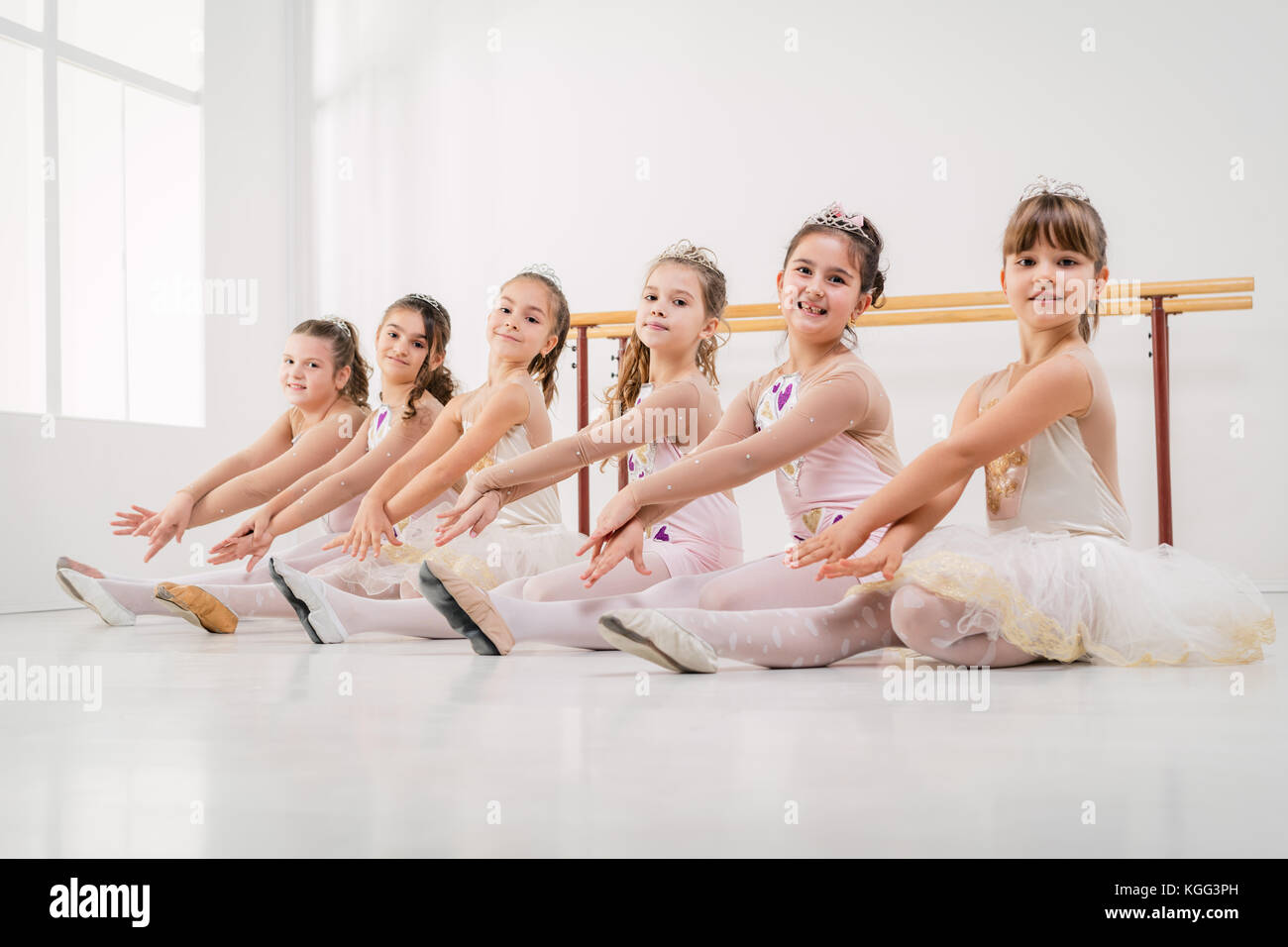 Les petites filles en robes posant ensemble à la classe de ballet. looking at camera. Banque D'Images