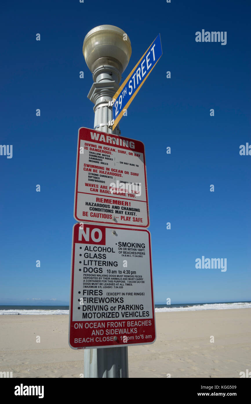 La lumière de la rue à la plage fin de la 29ème rue avec panneau d'avertissement sur les dangers sur la plage ainsi que les restrictions et les interdictions. Banque D'Images