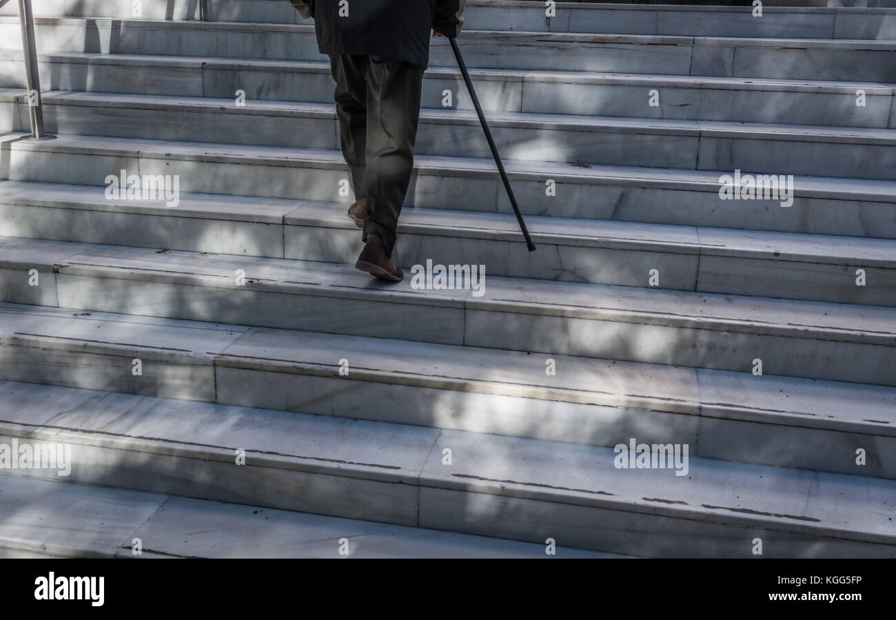 Un homme âgé à monter étapes avec stick Banque D'Images