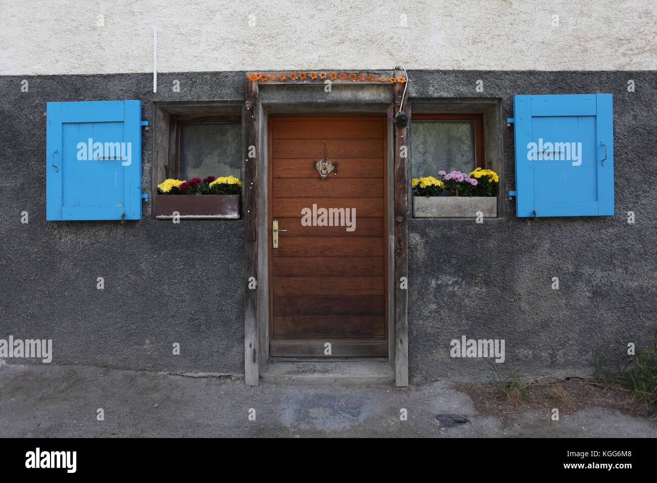 Une porte en bois avec des fenêtres bleues dans un village traditionnel de la Suisse en tant que partie de la tour du mont blanc fleurs dans les fenêtres. Banque D'Images