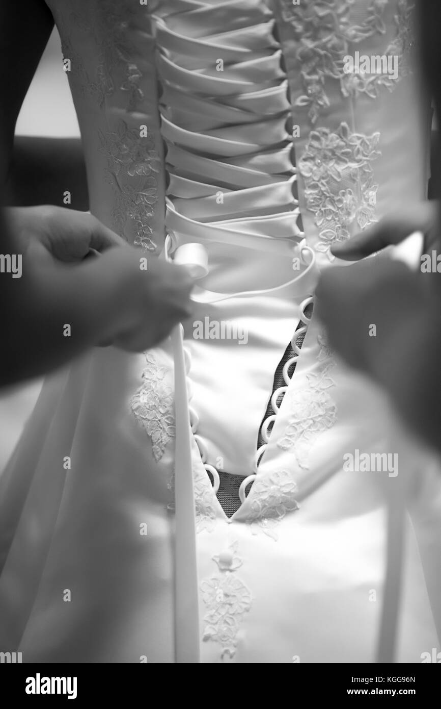 Bride standing avec son dos vers la caméra, les mains attacher sa robe de mariage, photo en noir et blanc Banque D'Images