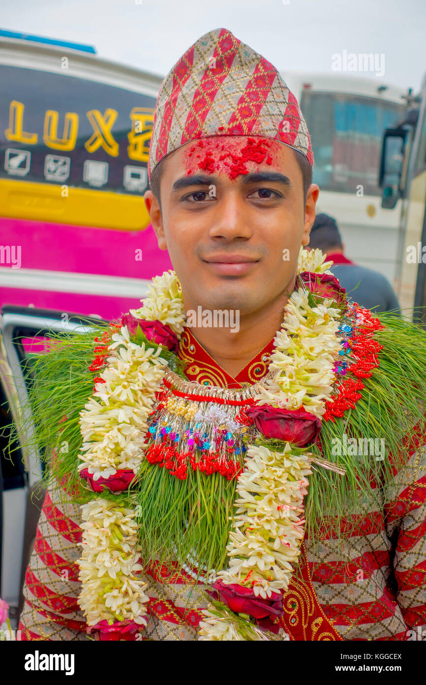 Pokhara, Népal, 10 octobre 2017 : portrait d'un bel homme portant des  fleurs autour du cou et portant des vêtements typiques et des villageois en  train de célébrer un mariage népalais à