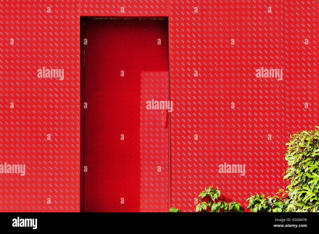 La porte rouge avec des feuilles vertes au coin des rues, de Singapour Banque D'Images