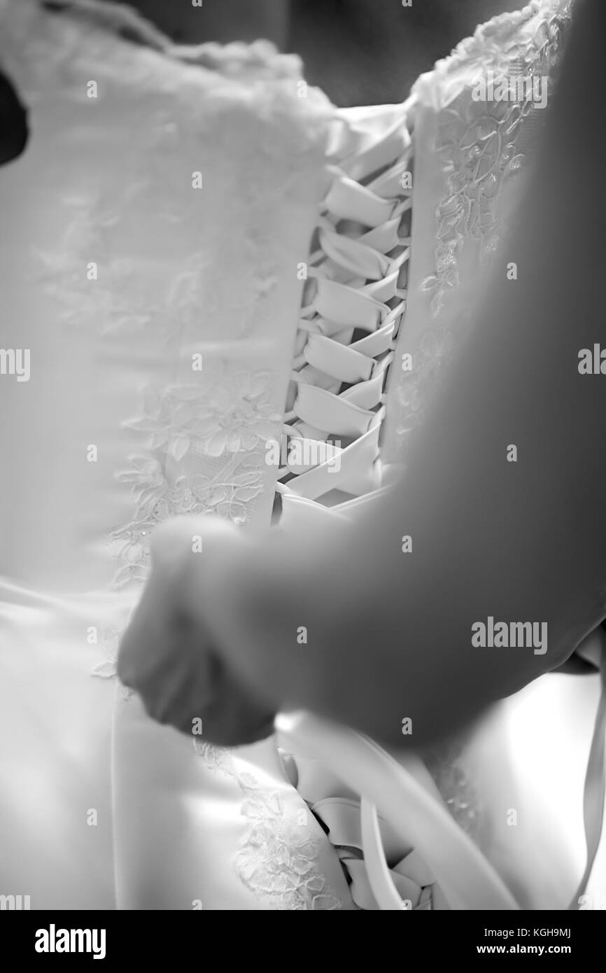Bride standing avec son dos vers la caméra, les mains attacher sa robe de mariage, photo en noir et blanc Banque D'Images