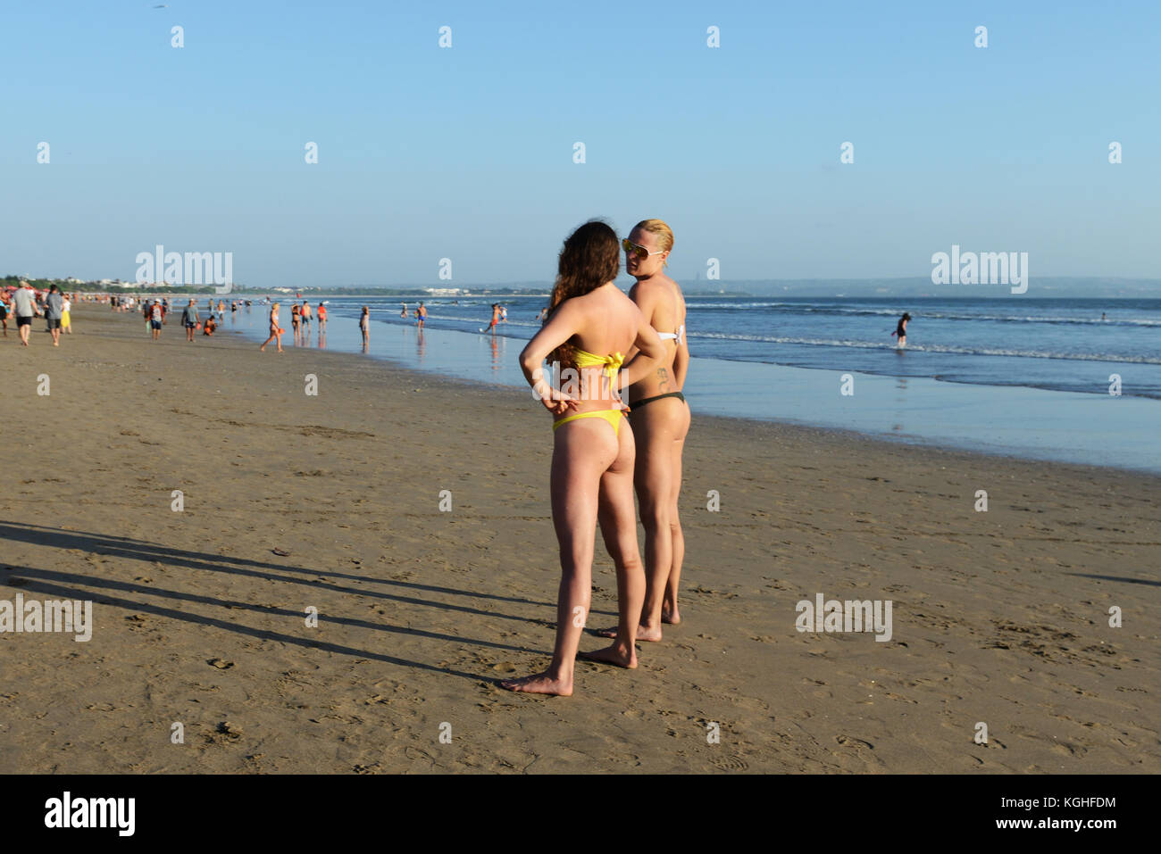 Young Caucasian women standing et de bronzage sur la plage de Kuta, Bali. Banque D'Images