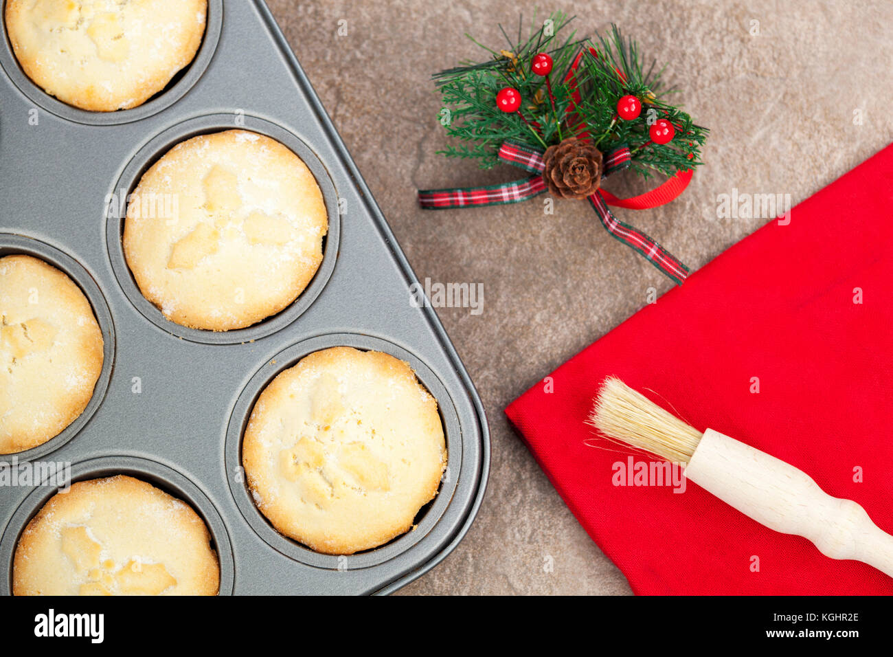 Brun Doré frais petits pâtés dans une plaque à pâtisserie avec motif de noël et d'un pinceau sur une serviette rouge Banque D'Images