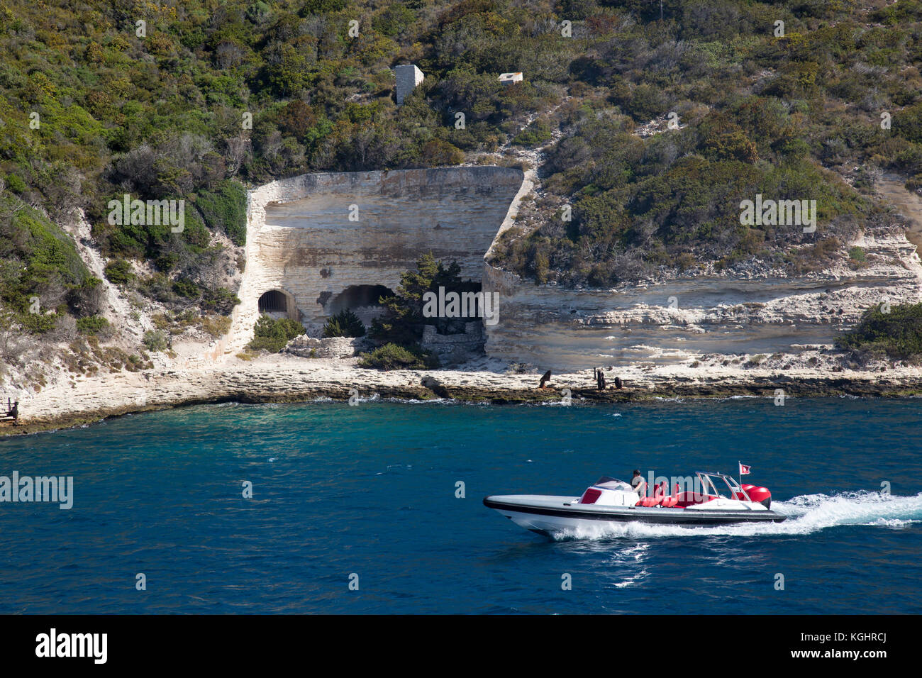 Excès de bateau à moteur dans la baie de Bonifacio sur fond de grottes dans les falaises de calcaire Banque D'Images