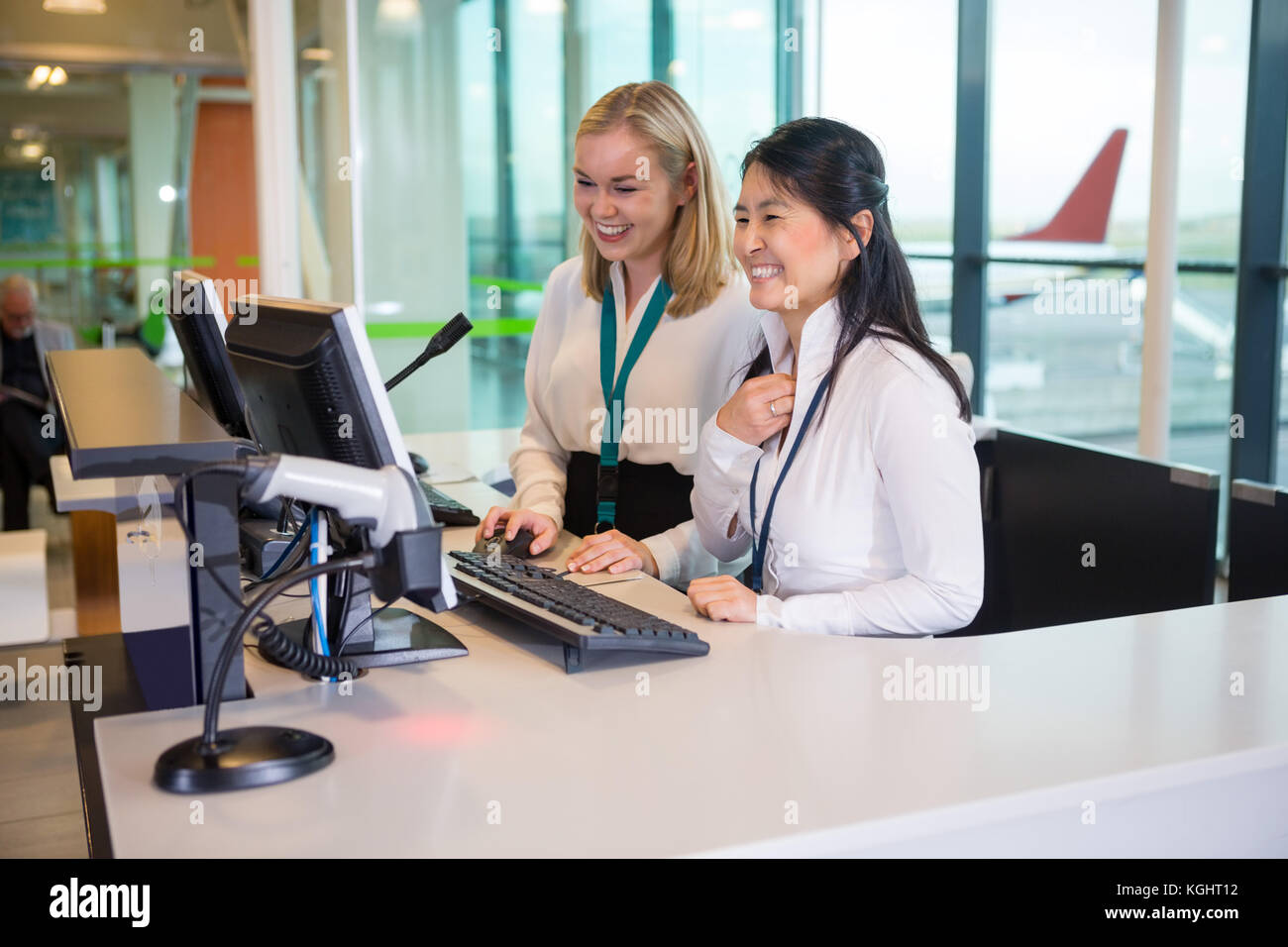 Réceptionnistes souriants working at desk in airport Banque D'Images