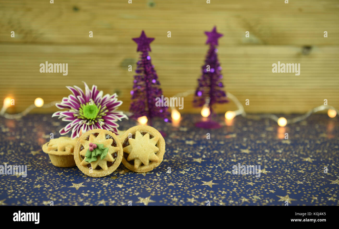 Noël Nourriture photographie image de petits pâtés anglais traditionnel avec des fleurs d'hiver et le scintillement des décorations de l'arbre et fairy lights in background Banque D'Images