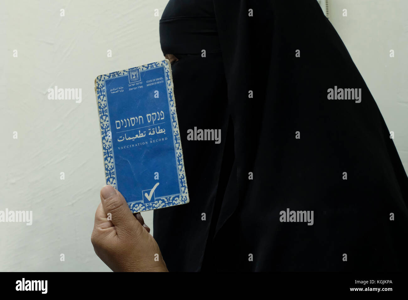 Une bédouine portant un niqab ou un niqaab tient son carnet de vaccination dans la ville de Beersheba, dans le sud d'Israël Banque D'Images