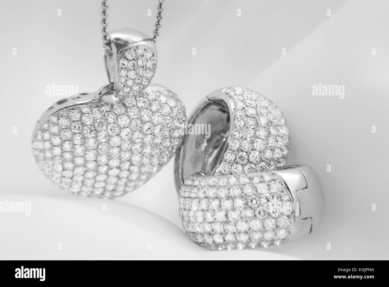 D'oreilles en or blanc et collier en forme de coeur avec diamants blancs sur fond flou doux Banque D'Images