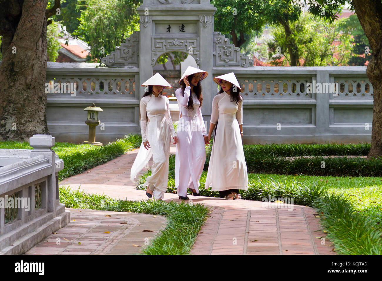 Les jeunes femmes vietnamiennes portant l'habit traditionnel Ao Dai et le chapeau conique... Non Emplacement ; jardin de Temple de la littérature à Hanoi, Vietnam Banque D'Images