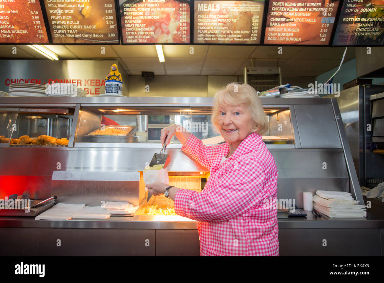 Femme âgée travaillant dans un poisson traditionnel britannique et chip shop, UK Banque D'Images