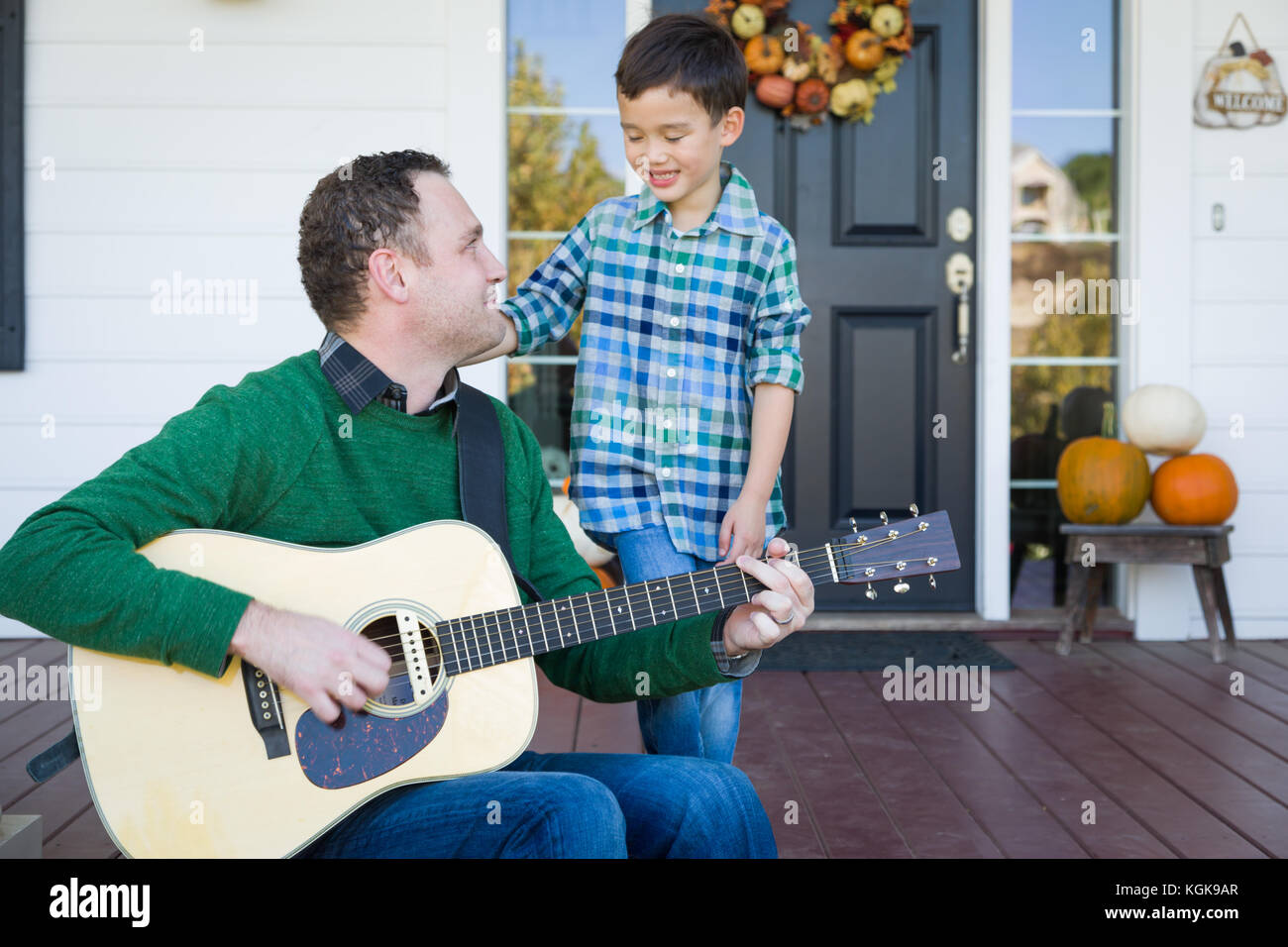 Young mixed race caucasienne et chinois fils chantant des chansons et à jouer de la guitare avec le père Banque D'Images