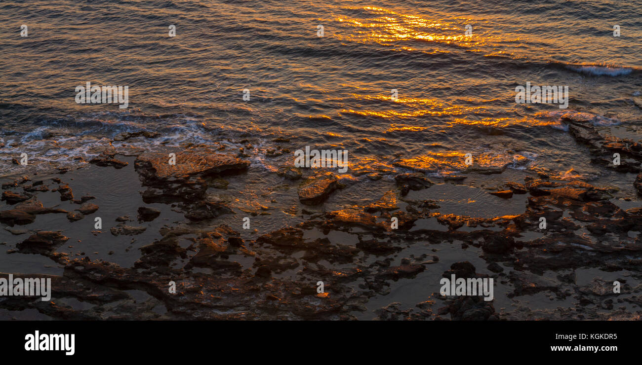 Rocky seashore et réflexions du soleil au coucher du soleil. Tourné en pomos, région de Paphos, Chypre Banque D'Images