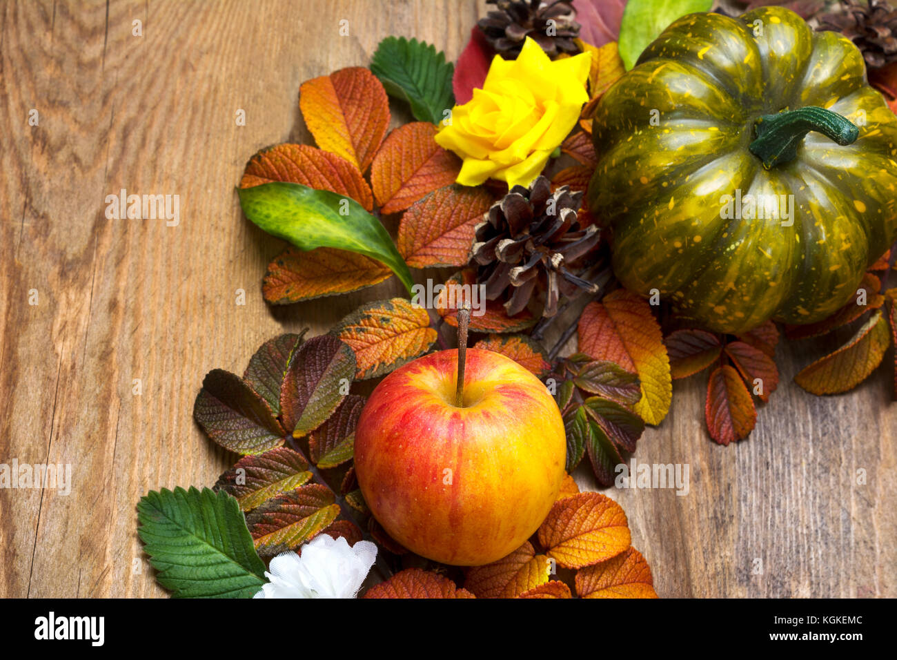 Couronne d'automne avec du potiron, vert pomme mûre, jaune roses en soie et les feuilles sur le fond de bois, vue du dessus Banque D'Images