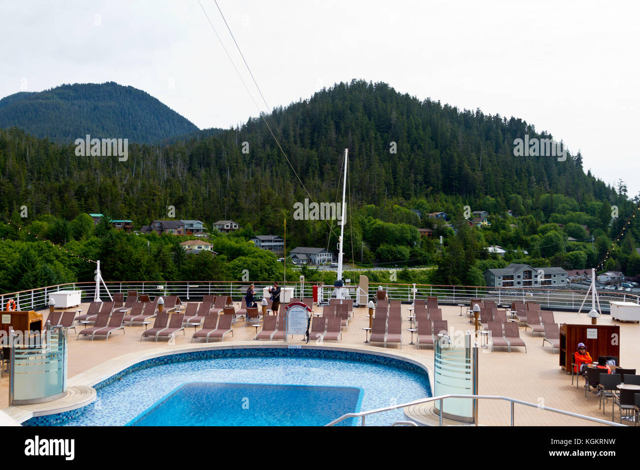 Le pont arrière du navire de croisière Eurodam montrant une piscine et de chaises longues et donnant sur de magnifiques collines boisées où les maisons sont nichées. Banque D'Images