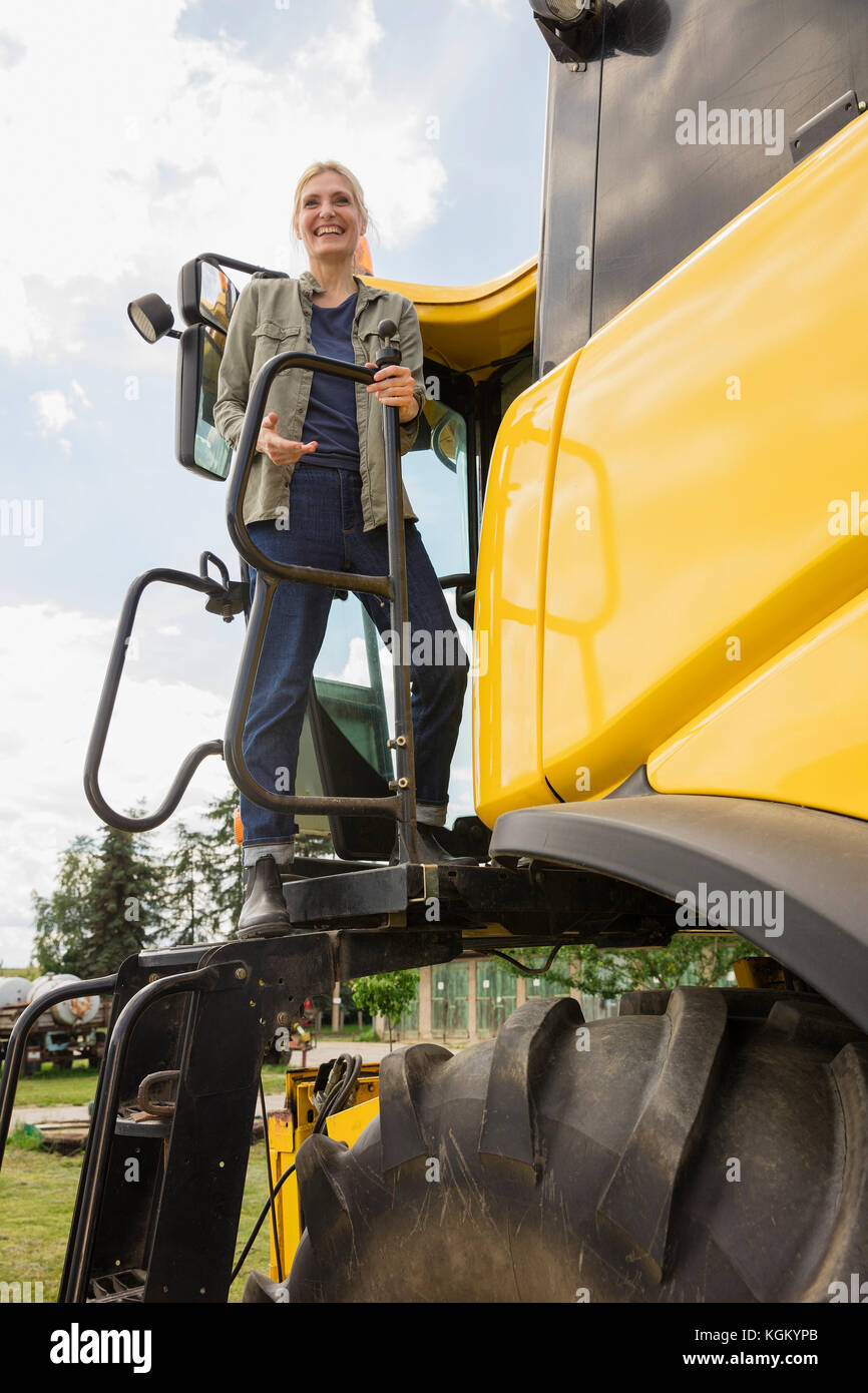 Low angle view of happy woman standing on tracteur contre ciel clair Banque D'Images