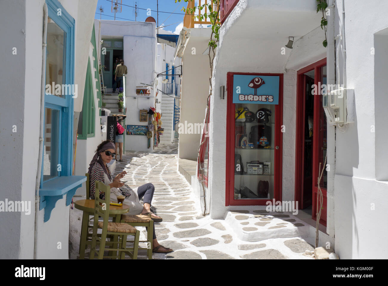 Jeune femme assise en face de sa boutique, ruelle dans la vieille ville de Naoussa, Paros, Cyclades, Grèce, Mer Méditerranée, Europe Banque D'Images