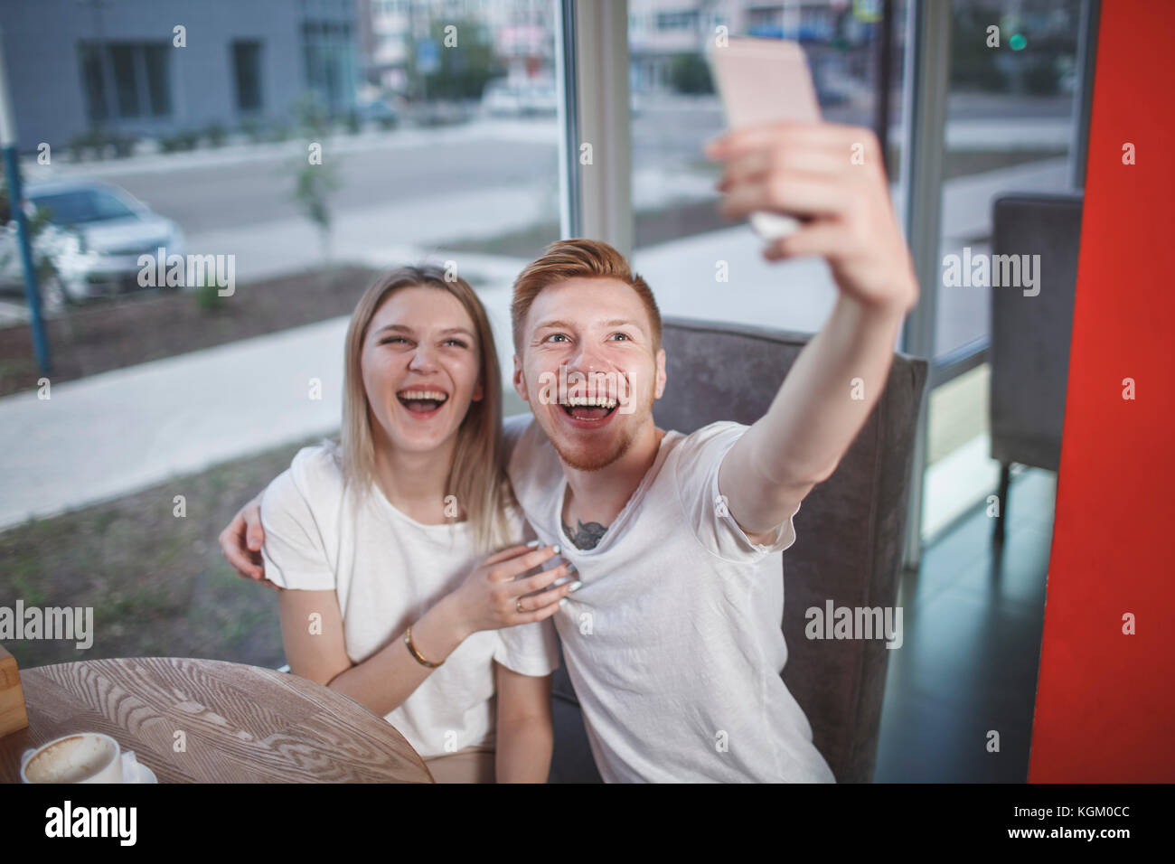 Portrait of happy young couple avec selfies mobile phone while sitting at restaurant Banque D'Images