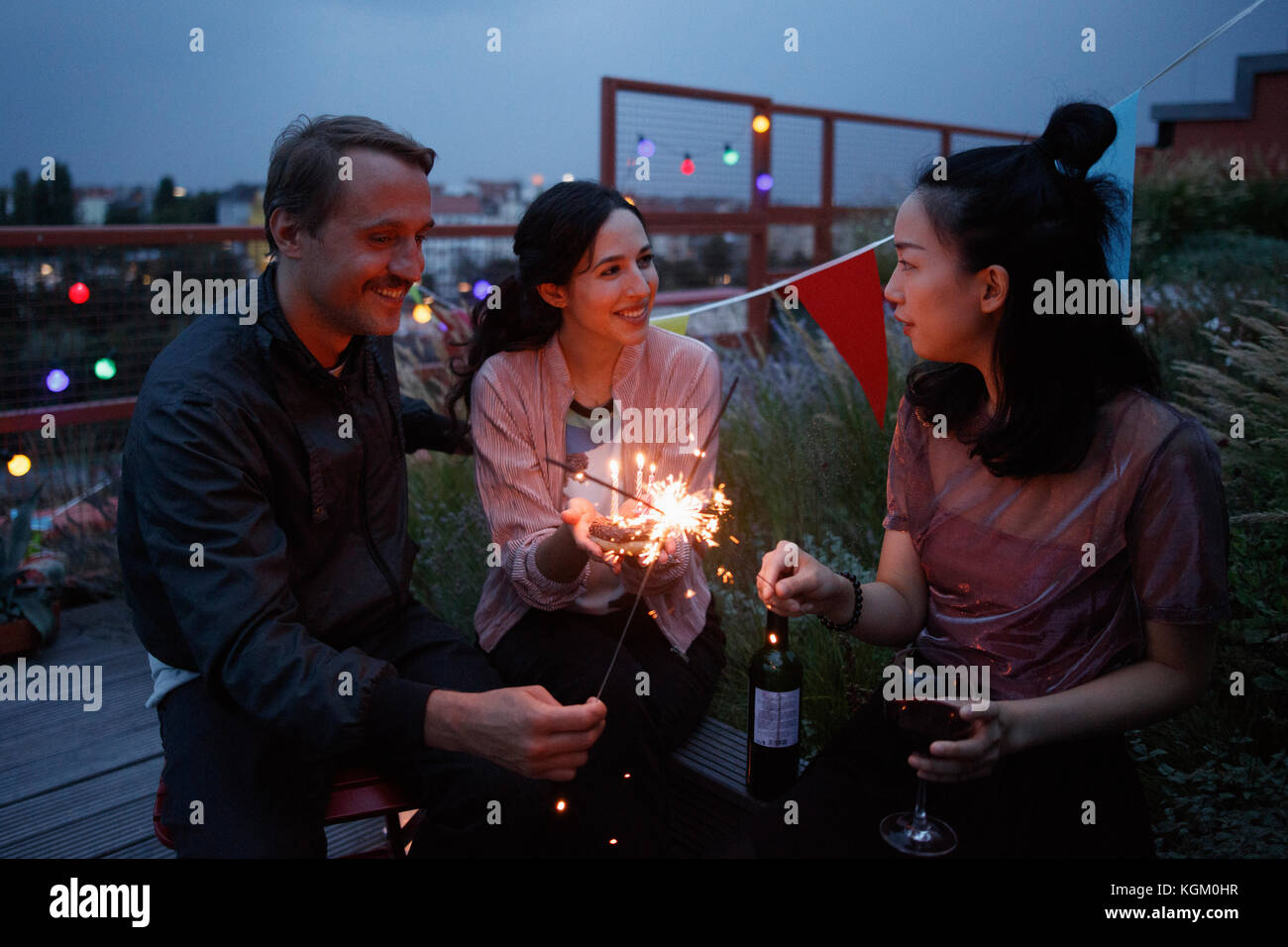 Heureux homme et femme friends holding sparklers on patio Banque D'Images