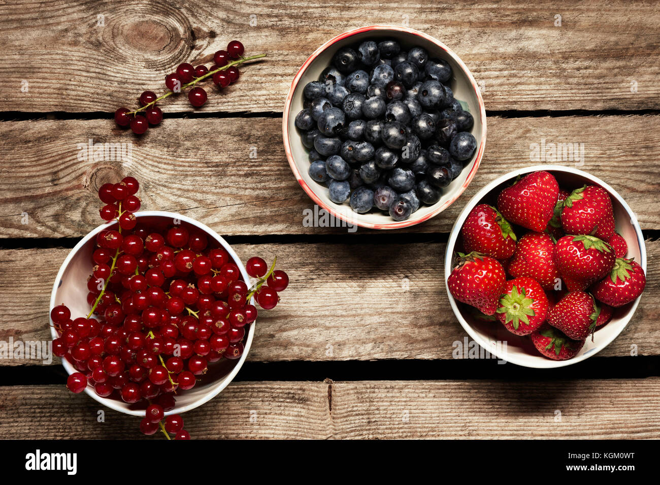 Tourné directement au-dessus de divers petits fruits rouges dans un bol sur la table en bois Banque D'Images