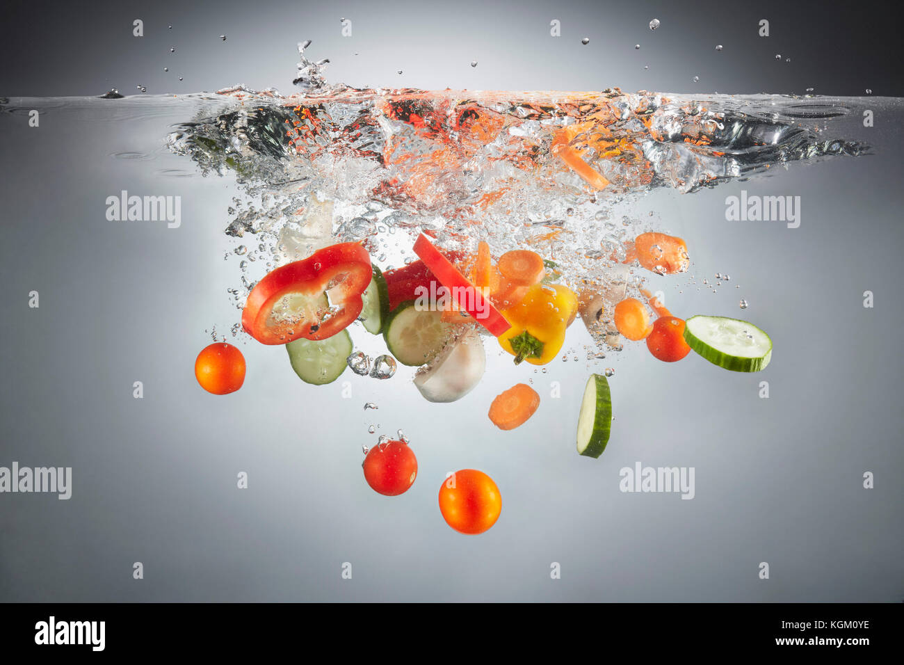 Close-up de divers légumes hachés dans les projections d'eau. Banque D'Images