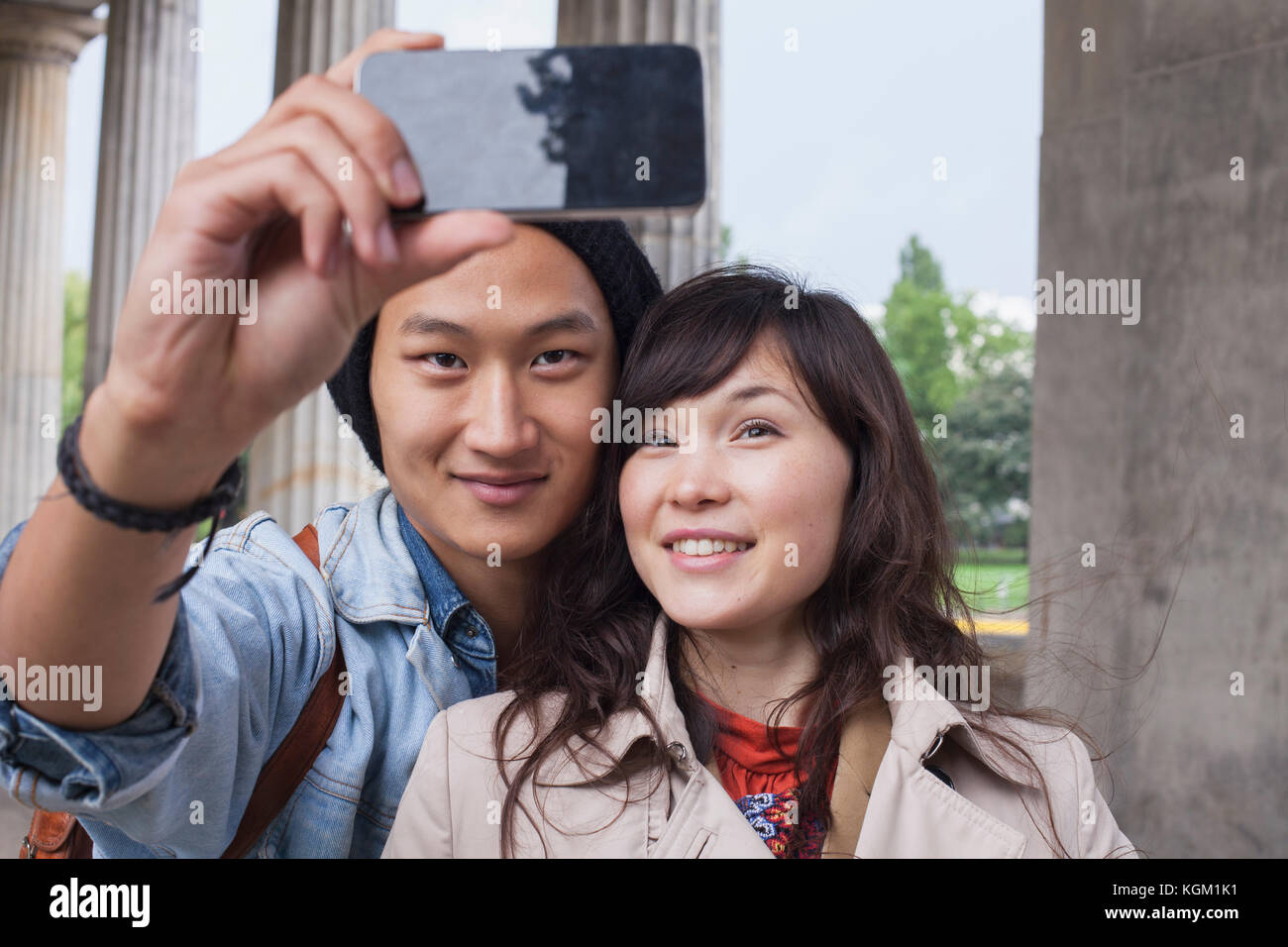 L'homme souriant en tenant avec de jeunes femelles ami selfies Banque D'Images