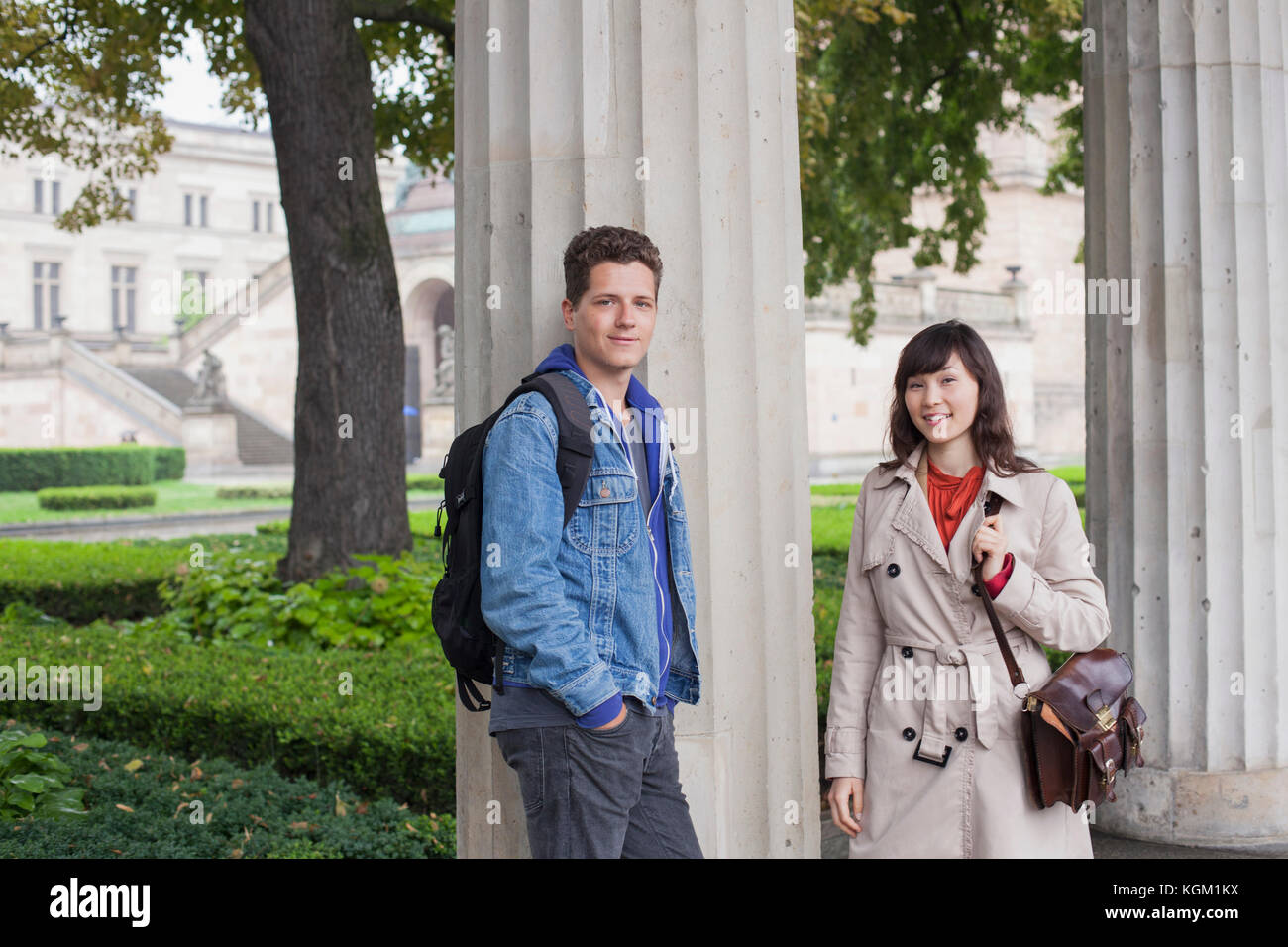 Portrait of smiling young friends standing par colonne, Berlin, Allemagne Banque D'Images